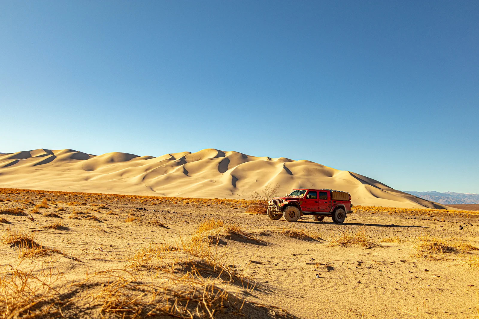 Orange Jeep Gladiator on a Death Valley overlook with vast desert basin and mountain ridges beyond